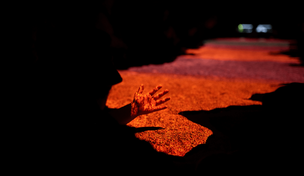 A person's hand bathed in the light of the projections inside the cave