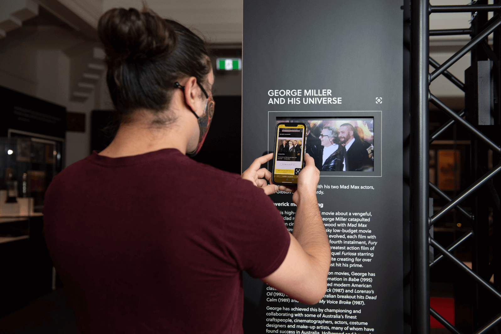 A person using the Spotlight mobile app to scan one of the exhibit's screens